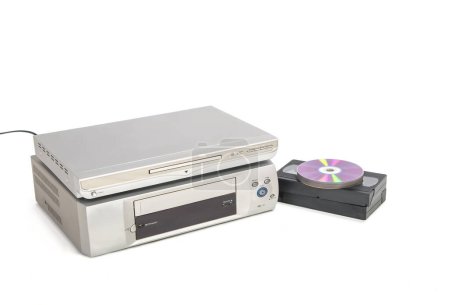 Dvd player over vhs player next to video tapes and cds isolated on white background.