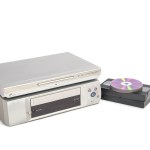 Dvd player over vhs player next to video tapes and cds isolated on white background.