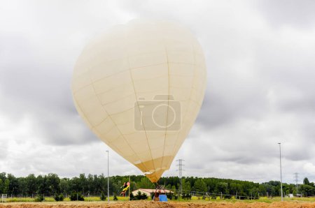 Balloon perched on the ground in a field during a cloudy day. Hot air balloon.