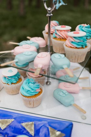 Pastel cupcakes and ice cream and popsicles on display for a celebration.