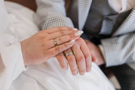 Frischvermählte halten sich an den Händen und präsentieren gemeinsam ihre eleganten Hochzeitsbänder