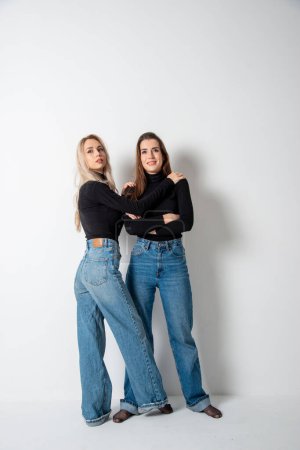 Photo for Two beautiful girls brunette and blonde posing in studio against gray - Royalty Free Image