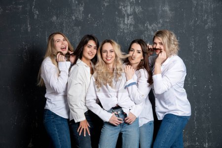 Téléchargez les photos : Jeunes femmes séduisantes en chemises blanches et en jeans posant en studio - en image libre de droit