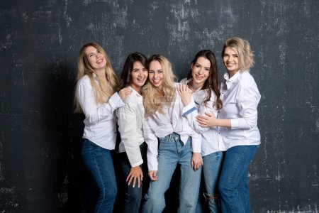 Foto de Young attractive women in white shirts and jeans posing in the studio - Imagen libre de derechos