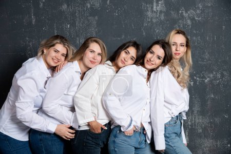 Foto de Young attractive women in white shirts and jeans posing in the studio - Imagen libre de derechos