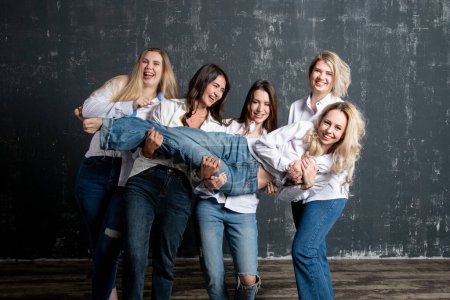 Téléchargez les photos : Young attractive women in white shirts and jeans posing in the studio - en image libre de droit