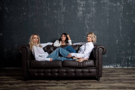 Photo for Beautiful women posing on a sofa - Royalty Free Image