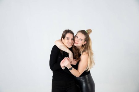 Téléchargez les photos : Deux jeunes femmes en vêtements noirs posant sur fond blanc - en image libre de droit