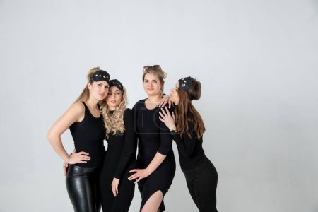 Foto de Sisters posing in studio, wearing black dresses against white background. Girls smiling and having fun. - Imagen libre de derechos