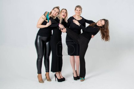 Foto de Hermanas posando en el estudio, vistiendo vestidos negros sobre fondo blanco. Chicas sonriendo y divirtiéndose. - Imagen libre de derechos