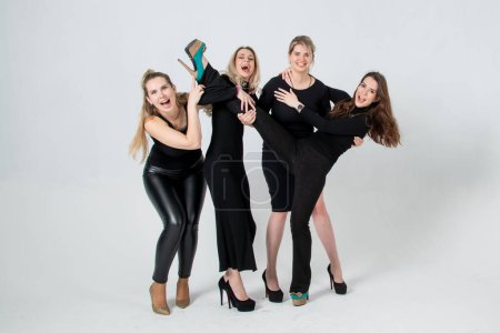 Photo for Sisters posing in studio, wearing black dresses against white background. Girls smiling and having fun. - Royalty Free Image