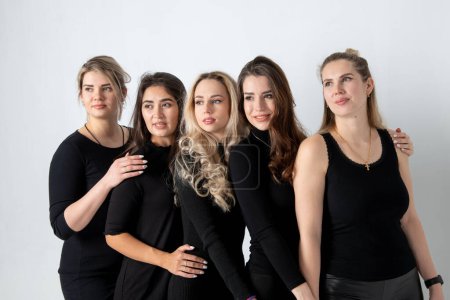 Foto de Sisters posing in studio, wearing black dresses against white background. Girls smiling and having fun. - Imagen libre de derechos