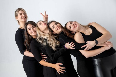 Téléchargez les photos : Sisters posing in studio, wearing black dresses against white background. Girls smiling and having fun. - en image libre de droit