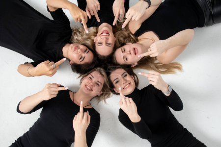 Foto de Grupo de mujeres jóvenes acostadas en círculo, riendo, abrazándose, divirtiéndose, con las manos - Imagen libre de derechos