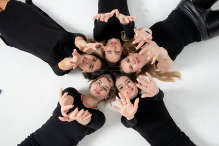 Téléchargez les photos : Group of young women lying in a circle, laughing, hugging, having fun, hands - en image libre de droit
