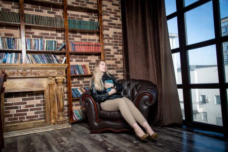 Photo for Beautiful girl with book sitting in chair - Royalty Free Image