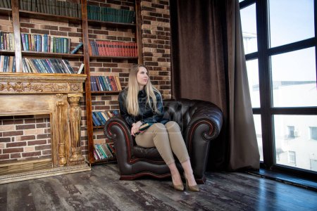 Photo for Beautiful girl with book sitting in chair - Royalty Free Image