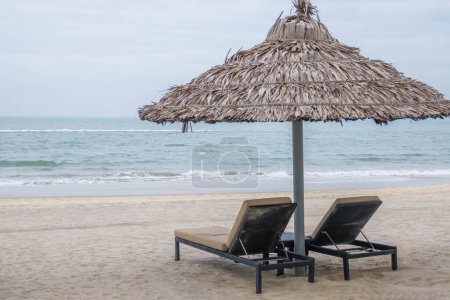 Foto de Pair of deck chairs under a palm umbrella in beautiful Cua Dai Beach in Hoi An, Central Vietnam - Imagen libre de derechos