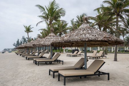 Foto de Row of deck chairs under a palm umbrella in beautiful Cua Dai Beach in Hoi An, Central Vietnam - Imagen libre de derechos