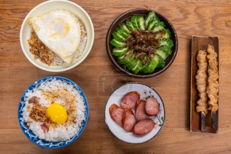 A wooden table with bowls of braised pork rice, eggs, vegetables, and sausage in Tainan, Taiwan