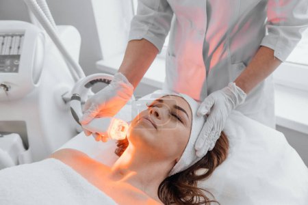 The hardware anti-aging procedure is an innovative method that helps restore skin health, get rid of wrinkles and increase its elasticity. Beautician uses LED therapy in beauty salon. High quality