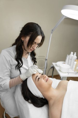 Photo for The photo reflects the therapeutic procedure of deep cleansing of the skin of the face, during which a beautiful woman finds harmony and relaxes in a beauty clinic. Cosmetologist works in the office - Royalty Free Image