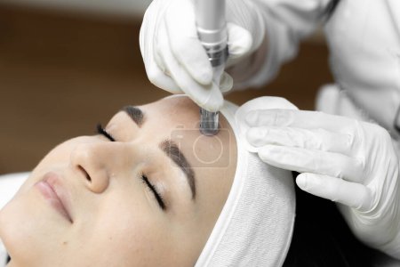 The photo conveys the moment of fractional mesotherapy, emphasizing the professionalism and experience of the cosmetologist in the beauty clinic. Beautiful close-up girl at the reception at the doctor