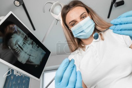 Foto de El dentista diagnostica responsablemente al paciente antes del tratamiento. Un paciente en una silla dental bajo la estricta supervisión de un dentista. Un médico en una clínica dental restaura una sonrisa. Foto de alta calidad - Imagen libre de derechos