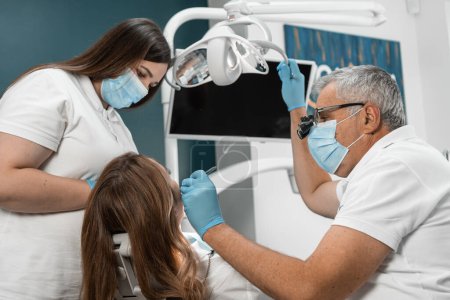 The doctor and dental assistant do their best to provide care and comfort for the woman in the dental chair, ensuring a painless and effective treatment process. High quality photo