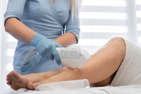 High-quality skin care, where an experienced cosmetologist performs photoepilation for smooth and attractive skin on the clients legs. Woman in the cosmetology office at the resort on vacation. High