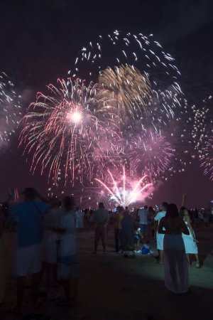 Foto de Fireworks on the beach. People watching watching the explosion of fireworks during the celebration of the new year. Santos City, Brazil. - Imagen libre de derechos