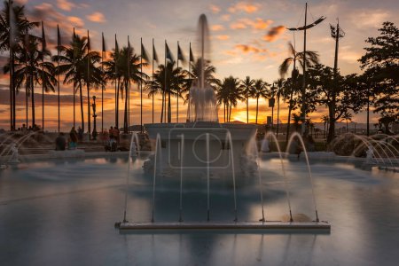 Foto de City of Santos, Brazil. Sunset on the beach. 9 de Julho water fountain, Praca das Bandeiras, Gonzaga beach. - Imagen libre de derechos