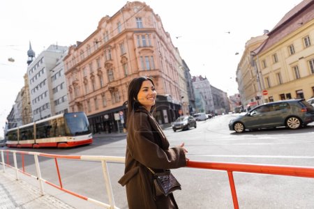 Happy traveler in coat standing near road on street in Prague 