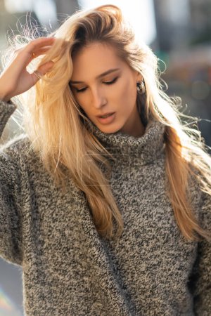 portrait of pretty young woman adjusting blonde hair in New York city 