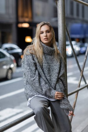 Téléchargez les photos : Femme élégante en chandail tricoté gris posant sur la rue urbaine de New York - en image libre de droit
