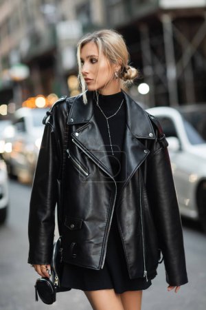 Porträt einer blonden Frau in stylischer Lederjacke, die auf einer urbanen Straße in New York wegschaut
