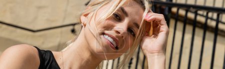 Sonnenschein im Gesicht einer fröhlichen Frau mit blonden Haaren, die draußen lächelt, Banner