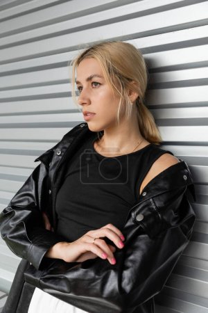 young blonde woman in leather shirt jacket standing near garage door in Miami 