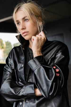 Photo for Portrait of blonde woman adjusting collar of leather shirt jacket - Royalty Free Image