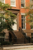 brick house with white windows and entrance with stairs near autumn trees on street in New York City Poster #638196718