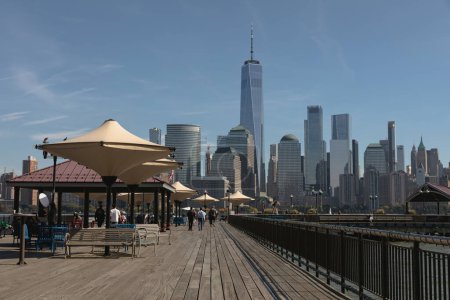 Foto de NEW YORK, USA - OCTOBER 13, 2022: people walking on embankment with scenic view of Manhattan skyscrapers - Imagen libre de derechos