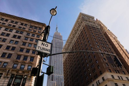 Foto de Low angle view of lantern with no turns sign near high-rise houses and Empire State building in midtown of New York City - Imagen libre de derechos