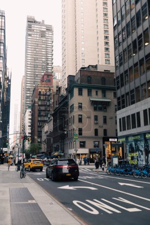 Foto de NEW YORK, USA - OCTOBER 13, 2022: pedestrians and traffic near buildings with shops in midtown - Imagen libre de derechos