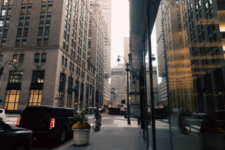 car road and sidewalk between modern buildings of urban street in New York City