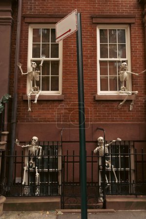 Backsteinhaus mit gruseligen Halloween-Skeletten an weißen Fenstern in New York City