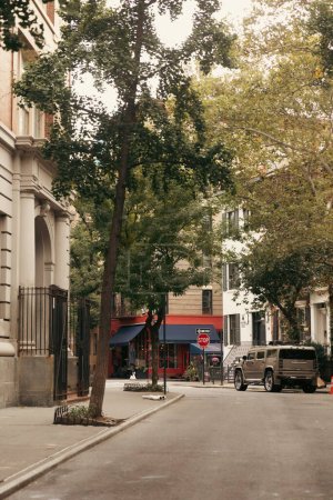 Foto de NEW YORK, USA - OCTOBER 13, 2022: stone buildings and car on road near trees in Brooklyn Heights district - Imagen libre de derechos