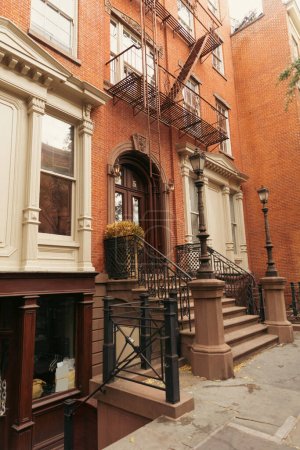 casa de ladrillo con escaleras y decoración de estuco blanco en la calle urbana de la ciudad de Nueva York