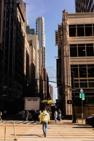 Foto de NEW YORK, USA - OCTOBER 11, 2022: People walking on crosswalk between buildings on street - Imagen libre de derechos