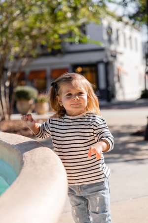 Kleinkind in langärmligem Hemd steht in der Nähe eines Brunnens auf der Straße in Miami 