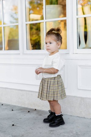 Foto de Longitud completa de niña en falda y camiseta blanca de pie cerca de la casa - Imagen libre de derechos